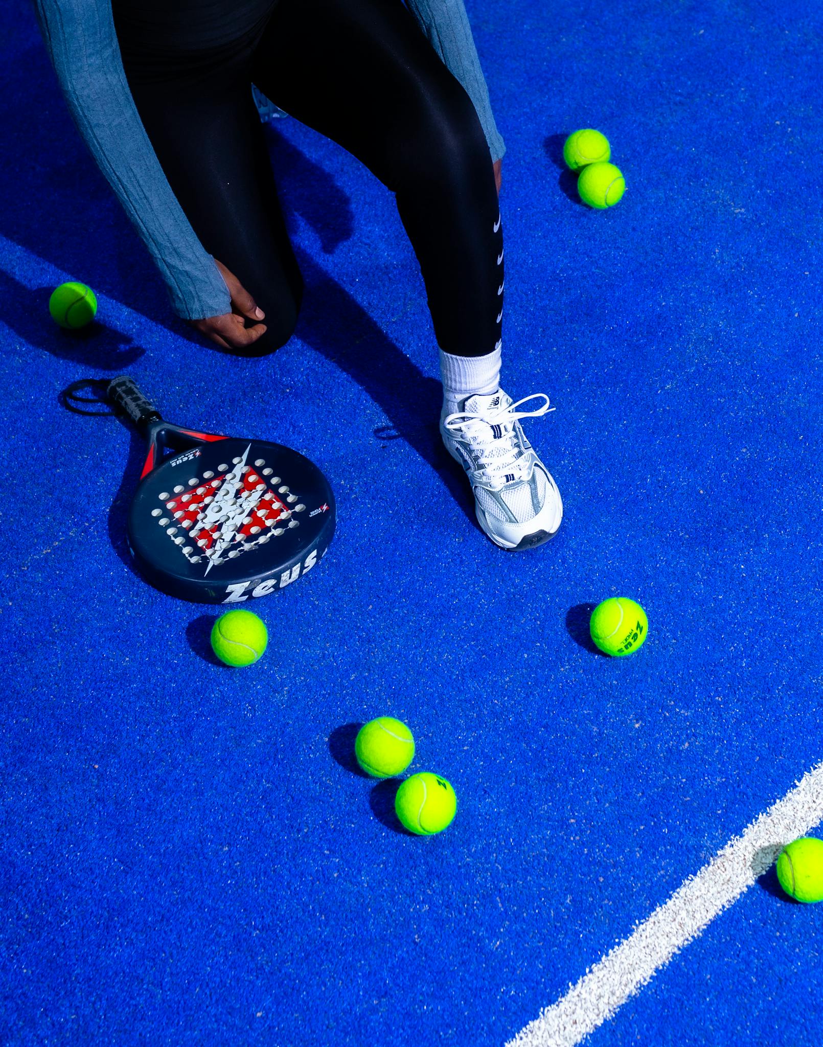 High-energy padel match on a striking blue court, showcasing racket, balls, and player movement.